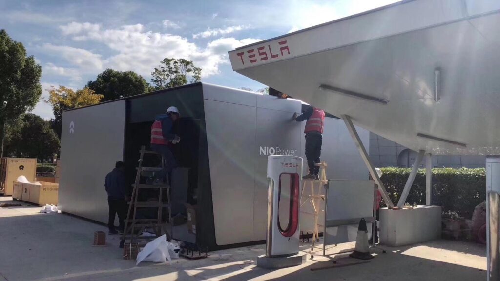 Stanice na výměnu baterií společnosti Nio vznikající v Číně roce 2018 přímo vedle nabíječky Supercharger společnosti Tesla (foto Reddit/JayinShanghai)